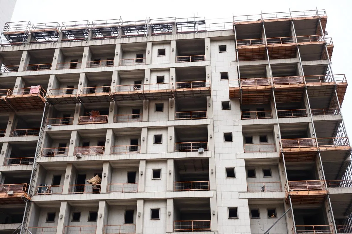Concrete floors and balcony openings of a mid-rise building under construction behind perimeter scaffolding